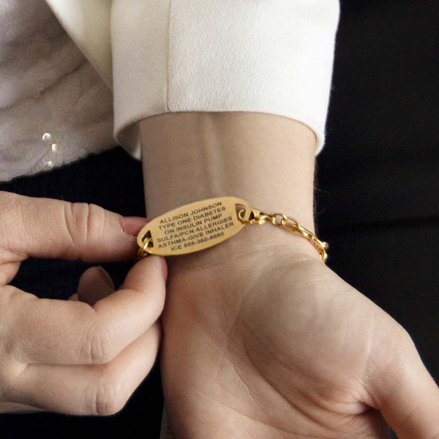 Woman showing custom engraved medical alert tag in stylish yellow gold