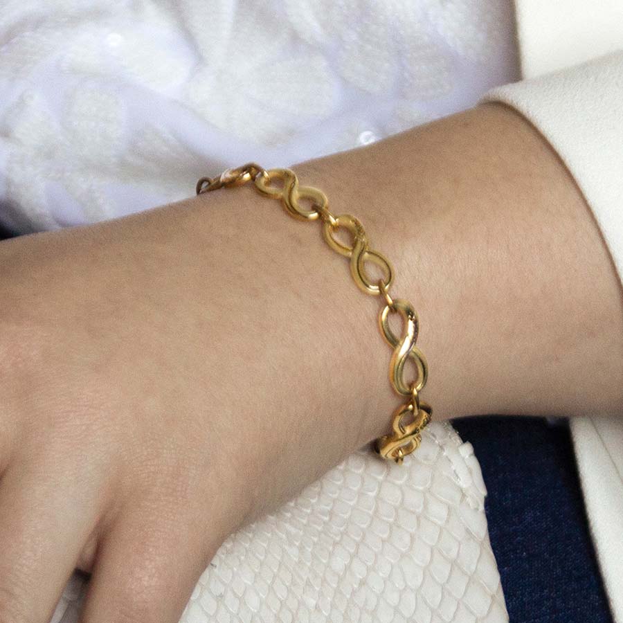 Woman wearing gold tone medical alert bracelet with infinity links