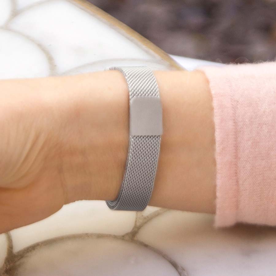 Woman wearing silver mesh medical alert bracelet with floral design and red medical caduceus symbol