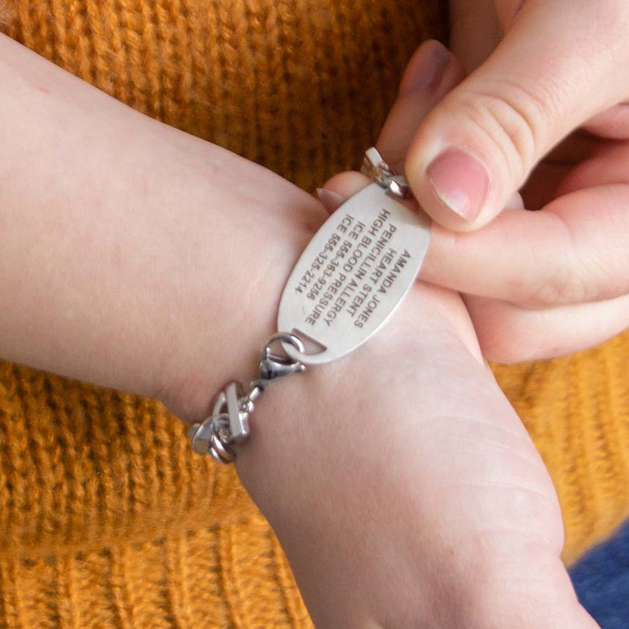 Woman showing custom laser engraved medical alert tag in silver tone