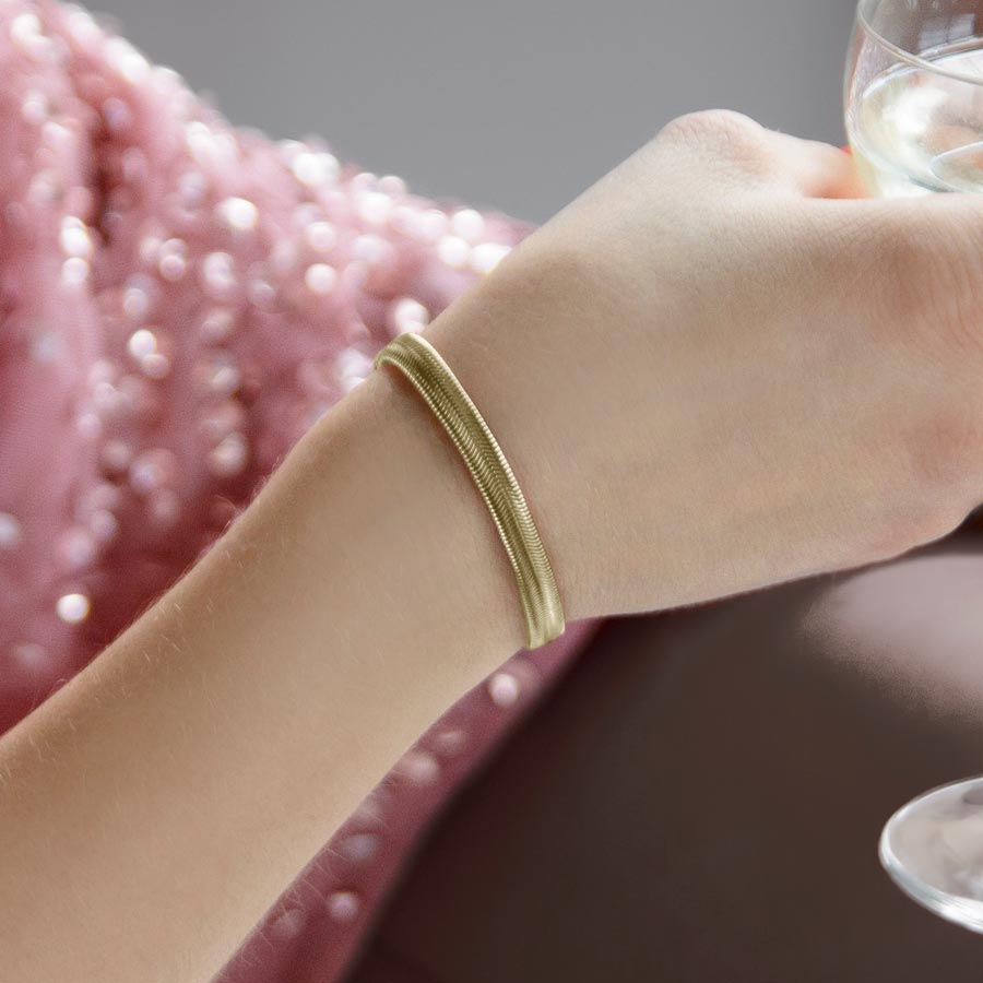 Woman sitting in chair wearing gold herringbone medical ID bracelet.