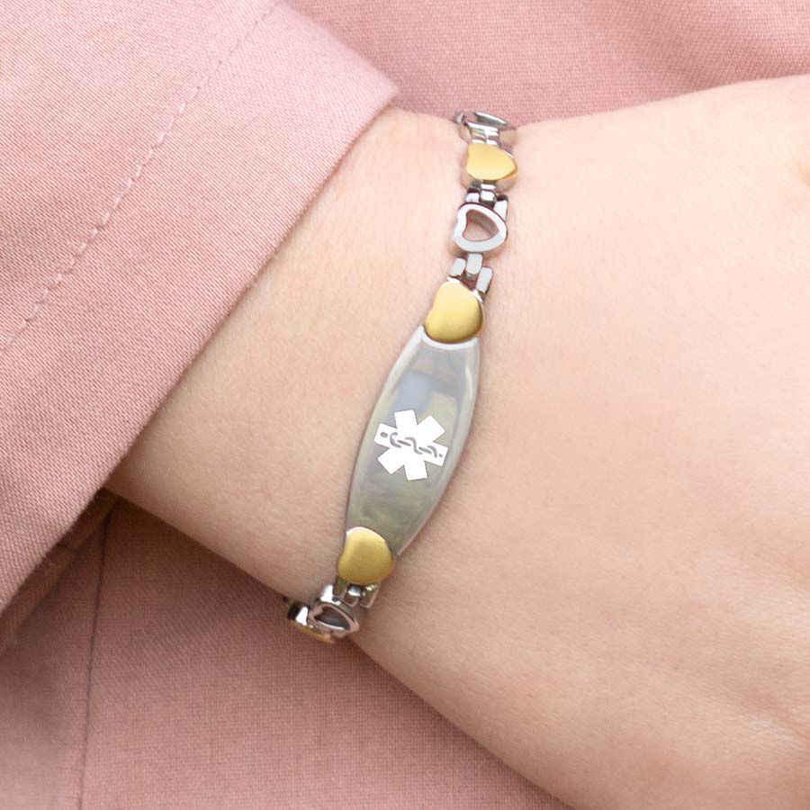 Woman wearing linked medical alert bracelet with heart-shaped links in silver and gold