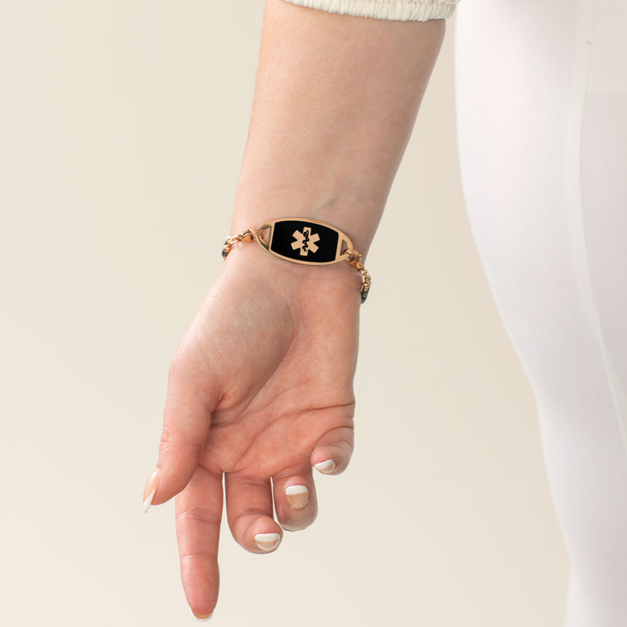 Woman showing decorative rose gold medical alert tag with black inlay and rose gold symbol