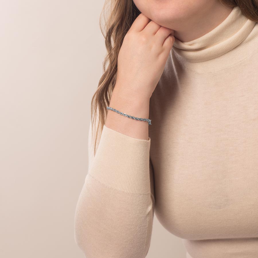 Woman sitting with hand under chin wearing silver tone rope chain bracelet