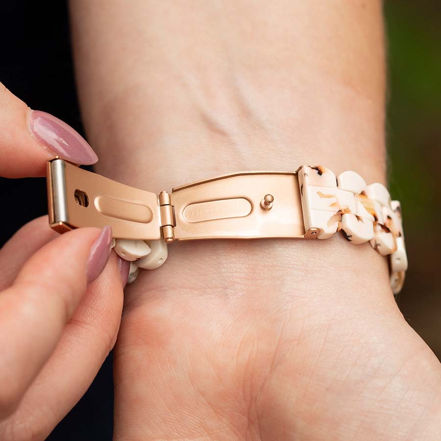 Woman wearing orange blouse with wrist turned showing the open rose gold clasp of resin medical ID bracelet. 