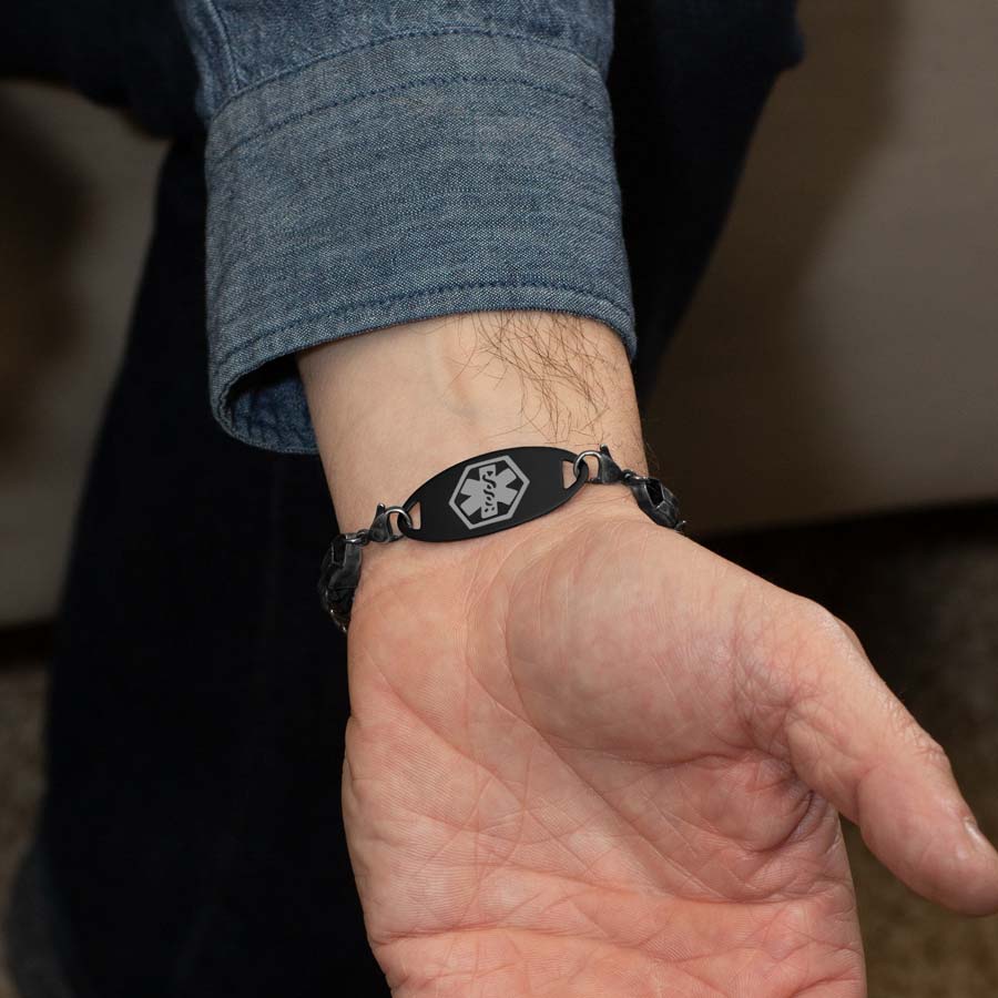 Man in denim shirt wearing antiqued woven stainless steel chain medical alert bracelet showing stainless steel medical ID tag with charcoal medical symbol.