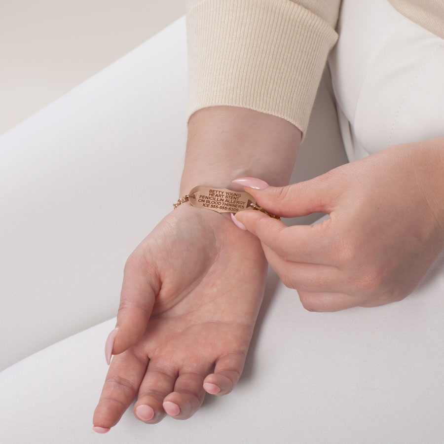 Woman showing custom laser engraving rose gold medical ID tag with decorative edges