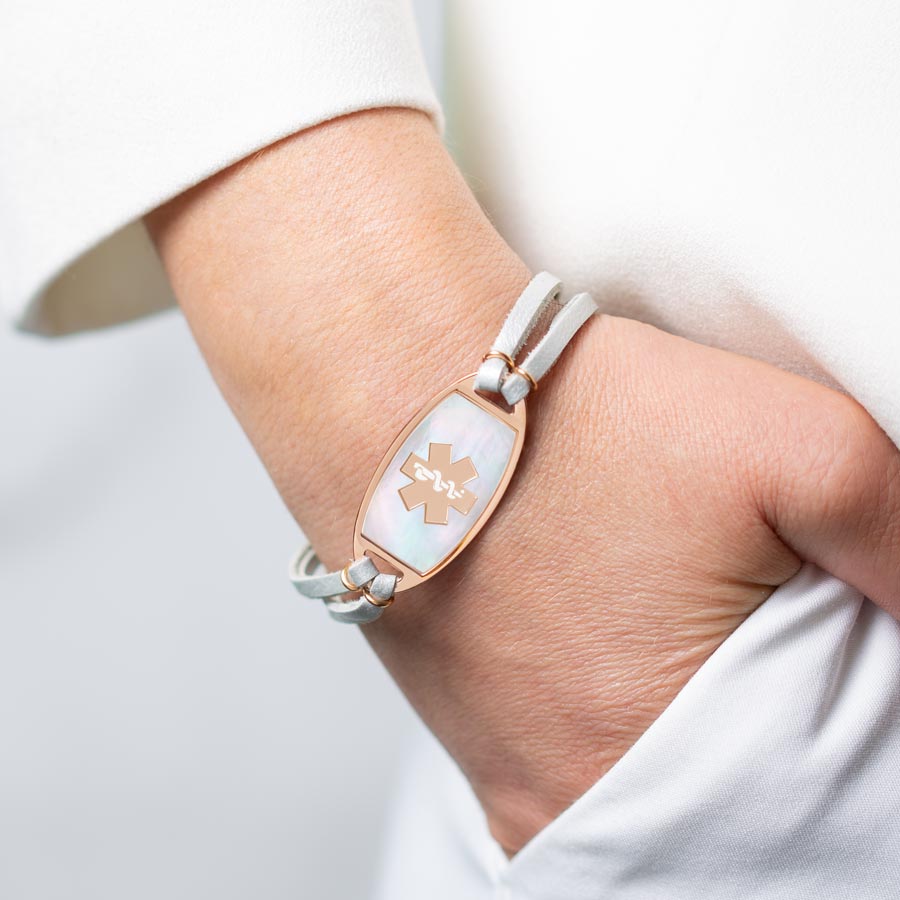 Woman with hand in pocket wearing pearlescent leather and rose gold mother of pearl medical ID bracelet.