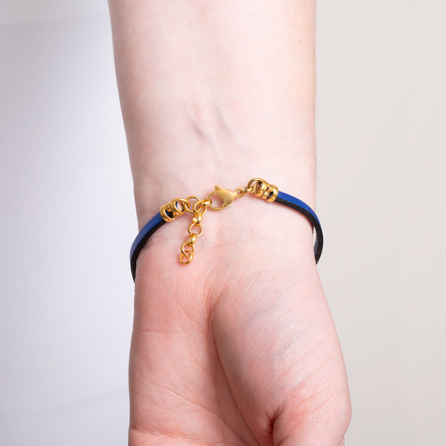 Navy blue metallic leather bracelet on arm showing the gold tone adjustable chain and lobster clasp that sits opposite the med ID tag.