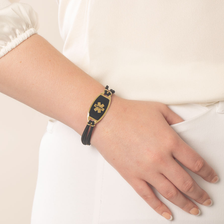 Woman wearing medical ID bracelet with black suede and gold accents