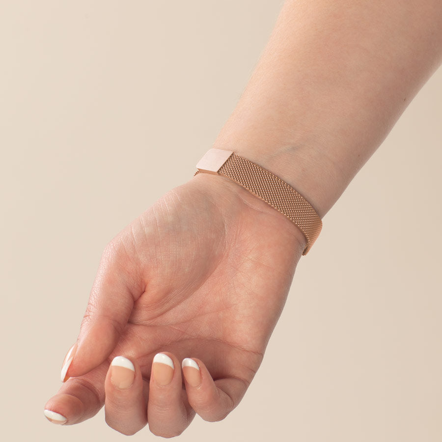 Woman showing magnetic clasp on rose gold tone stainless steel mesh band.