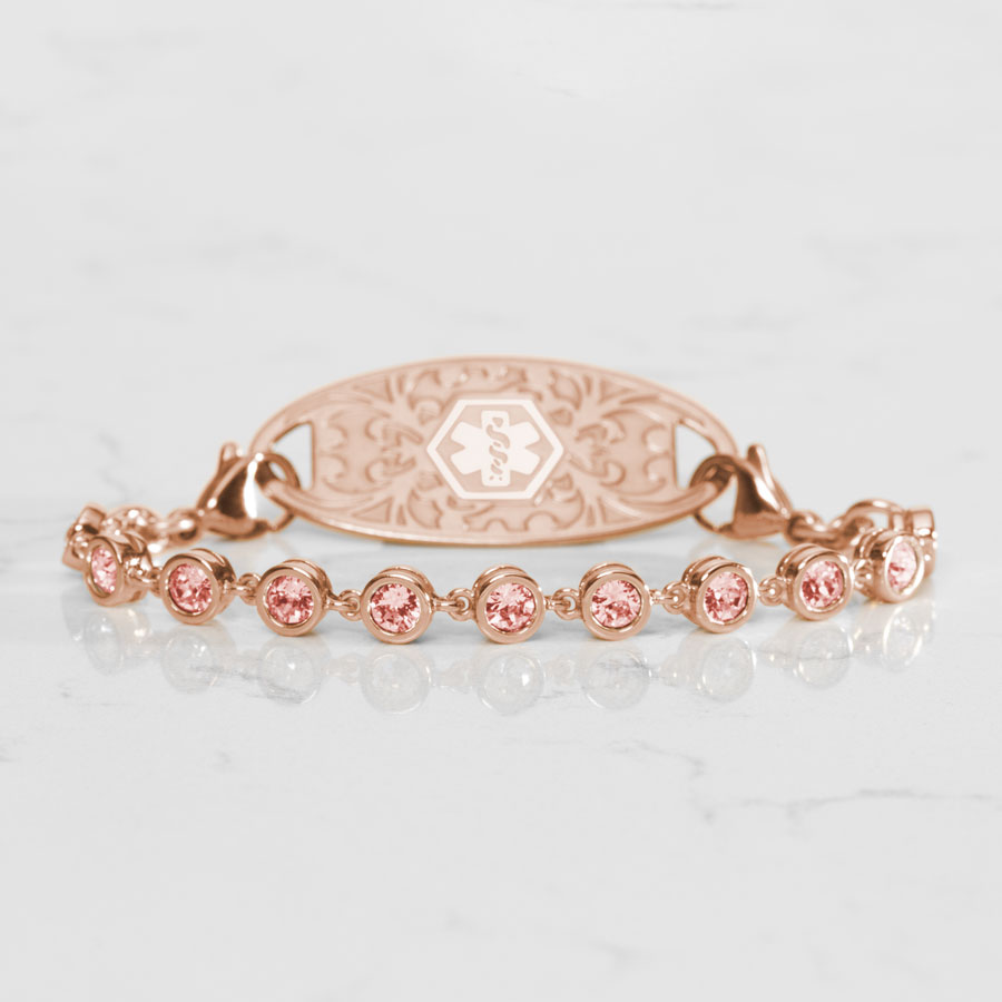 Ella Medical ID Bracelet in Rose Gold with round, bezel set, Light Rose tone Cubic Zirconia Crystals paired with a Rose Gold Medical ID Tag with Rose Gold InLay. Placed on a White Marble Table.