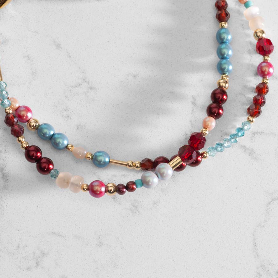 Close up of Red, Blue and Gold Beads of medical ID bracelet on white marble counter.