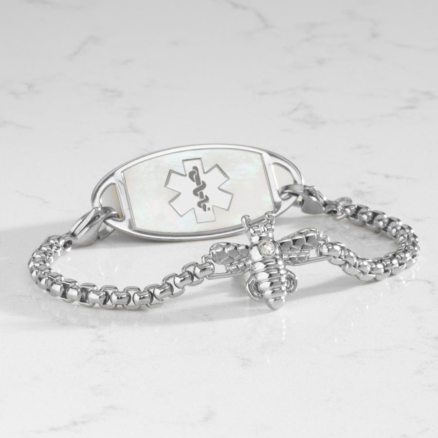 Silver toned box chain bracelet featuring a honey bee centerpiece with crystal. Attached to a silver tones medical ID tag featuring inlaid mother of pearl.