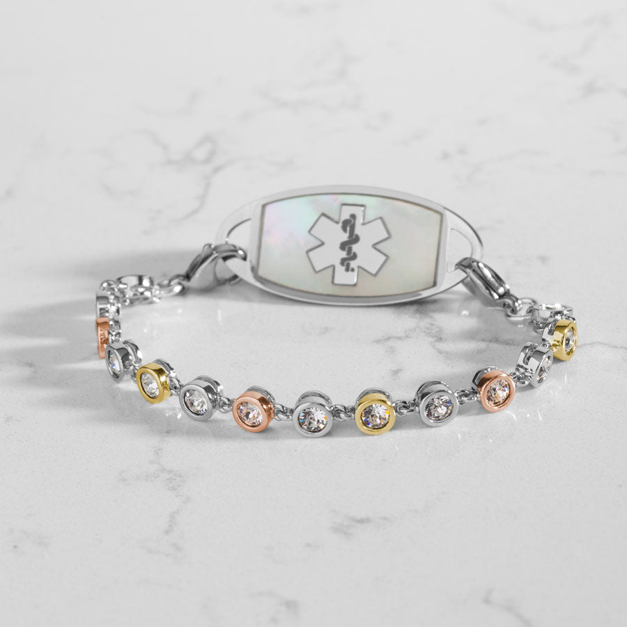 Bracelet featuring individually set, round cubic zirconia crystals, in alternating silver, rose and gold tones. Attached to a silver and gold medical ID tag.