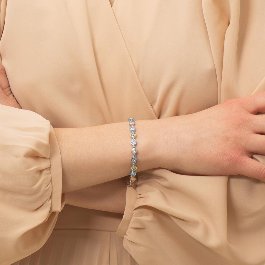 Woman wearing mixed metal bracelet featuring individually set, round, cubic zirconia crystals.