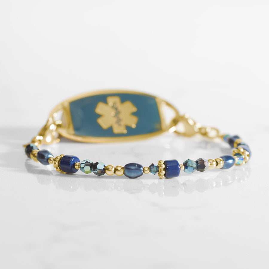 Blue and gold beaded medical ID bracelet on jewelry elastic with gold tone lobster clasps and sapphire blue decorative med ID tag.