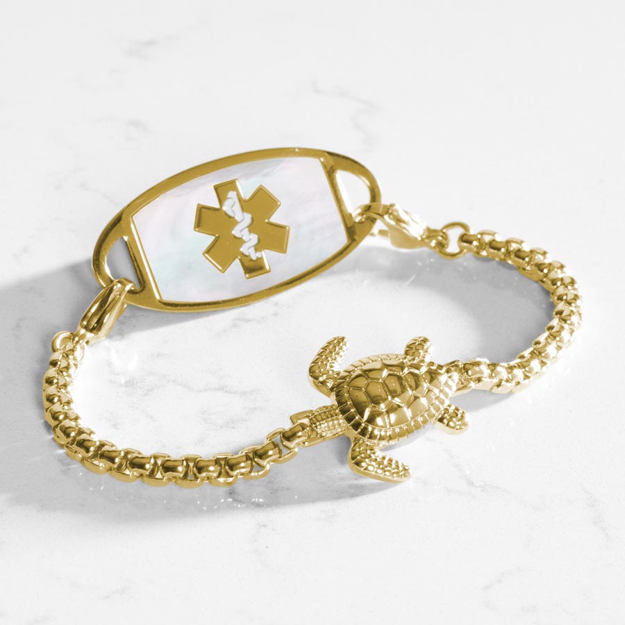 Gold tone box chain bracelet featuring a sea turtle centerpiece, attached to a gold tone medical ID with mother of pearl inlay.