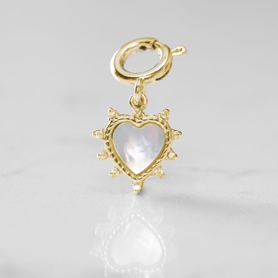 The mother of pearl inlay glows on this heart shaped charm, displayed on a white marble counter