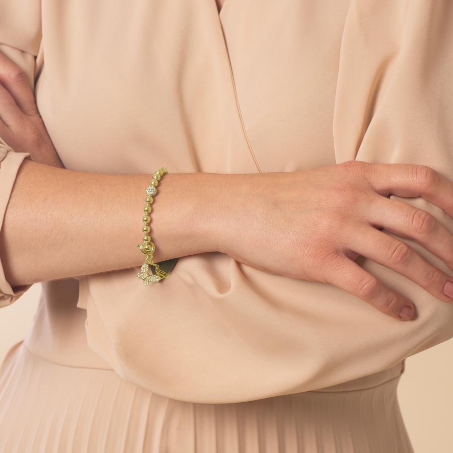 An elegant woman wearing a gold, butterfly shaped charm.