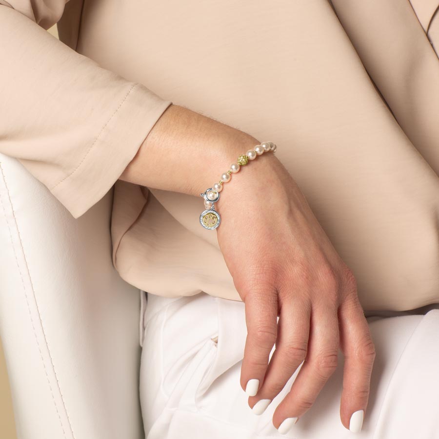 Elegant woman wearing a silver bracelet with silver and gold paw cut out charm attached