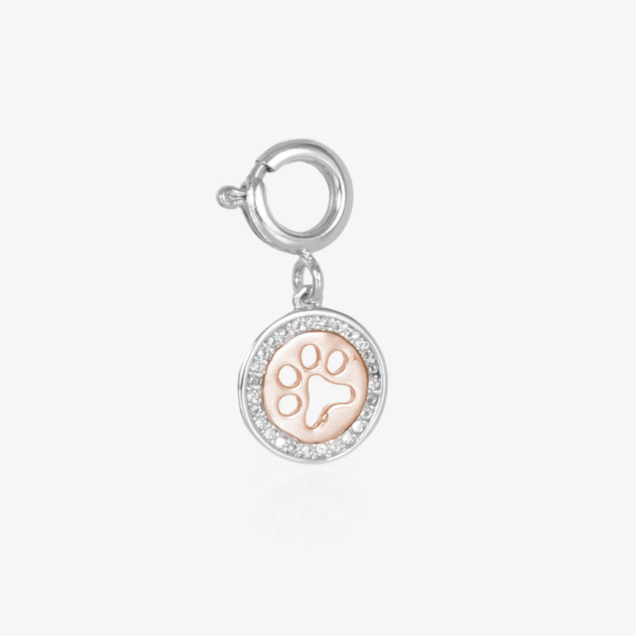 Attachable Charm featuring a cutout paw print encircled with clear, pave-set cubic zirconia crystals on Silver and Rose Gold. Measurements showing a height of 1-inch and width of 1/2-inch