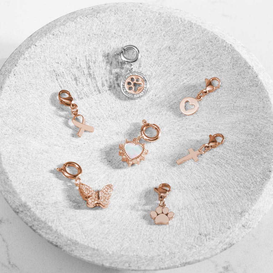 Many Rose Gold and Silver Charms in a soap stone dish.