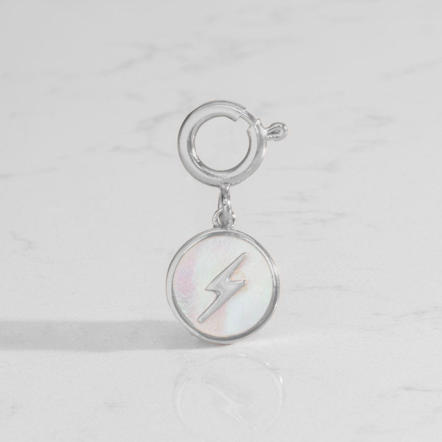 Round, silver tone harm, featuring a mother of pearl inlay with silver lightning bolt