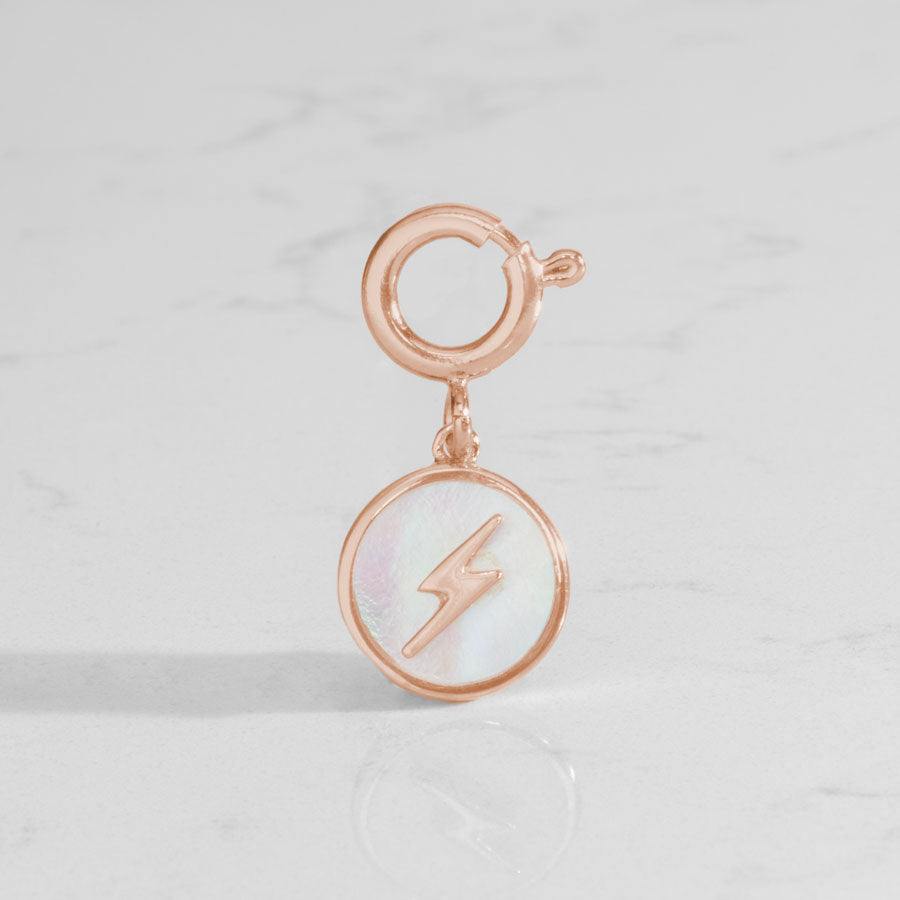 Round, rose gold tone charm, featuring a mother of pearl inlay with rose gold lightning bolt.