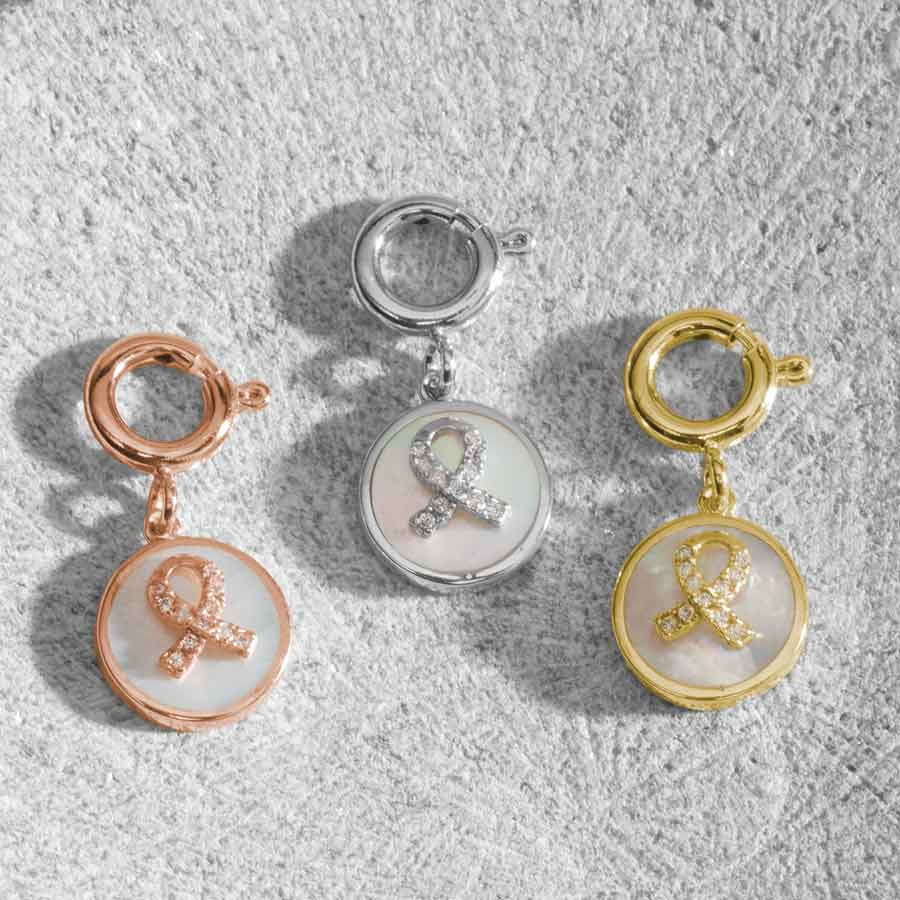 Thre round charms, faturing awareness ribbon inset with crystals on a field of inlaid mother of pearl. Shown in Rose, Silver and gold.