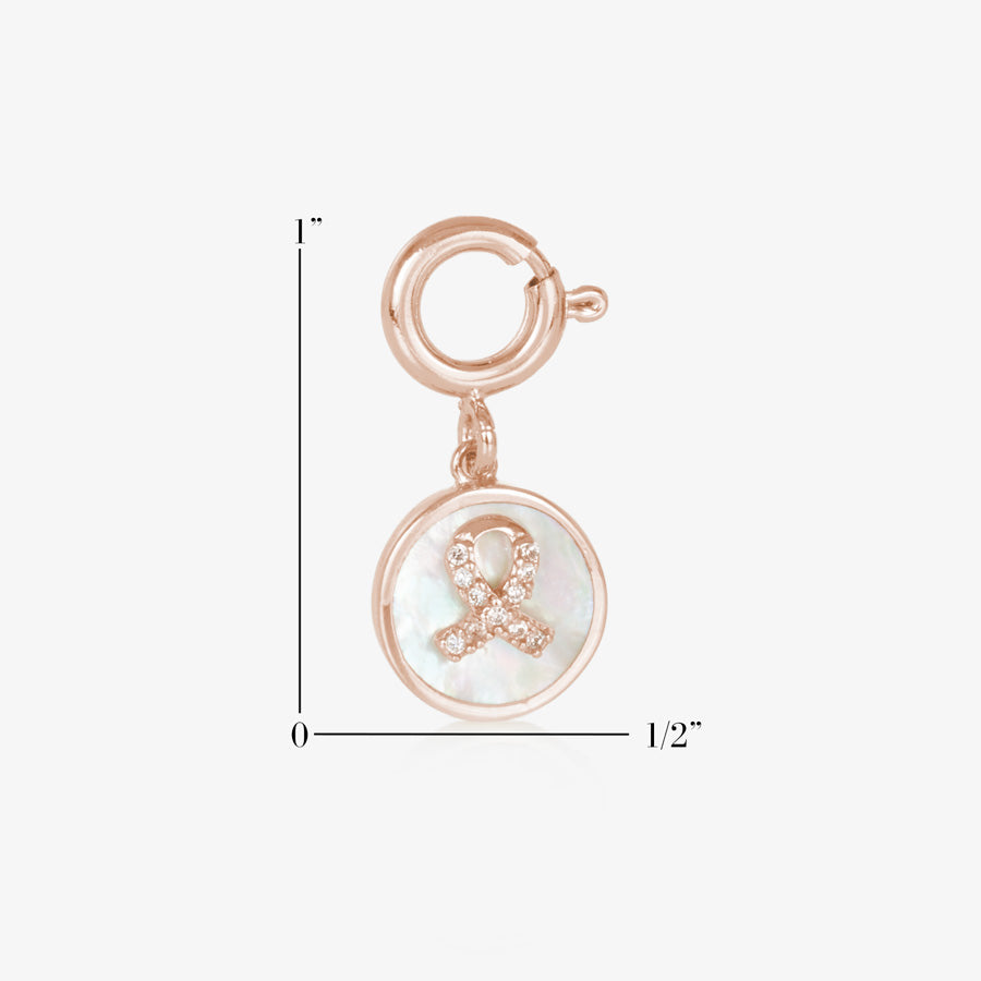 Rose gold tone round charm with mother of pearl inlay and rose gold awareness ribbon with inset crystals. SHowing measurements of one inch by one half inch.