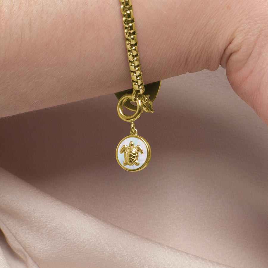 A woman wearing a gold toned sea turtle charm.