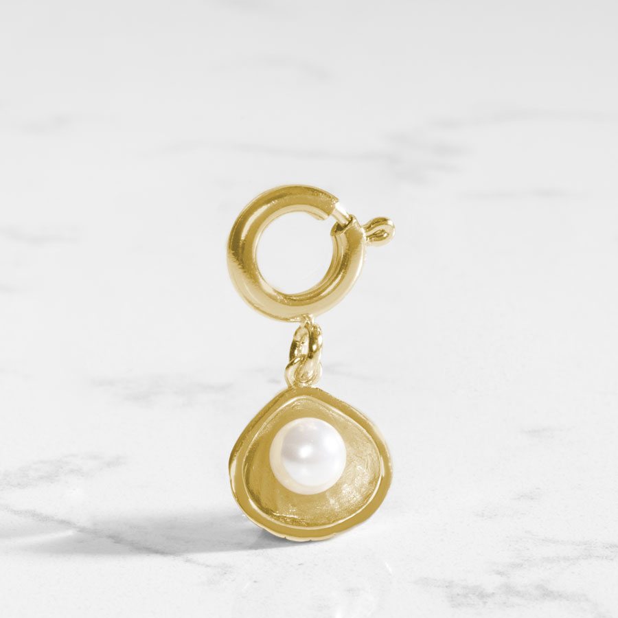 12k gold plated open oyster shell charm featuring a single, lustrous pearl, on a marble table