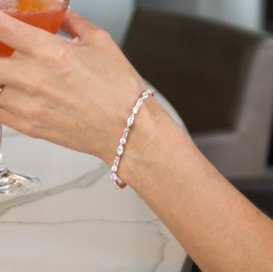 Woman wearing rose gold tone med ID bracelet with round, rectangle, and oval clear cubic zirconia crystals.