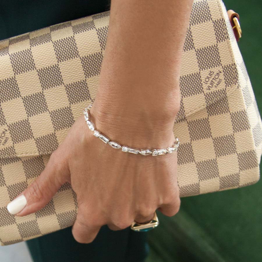 Woman wearing Cantata Medical ID Bracelet showing front view of 3 shapes of cubic zirconia. Carrying fashion purse