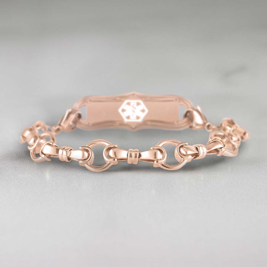 Rose gold bridle chain medical alert bracelet with decorative alert tag on marble background