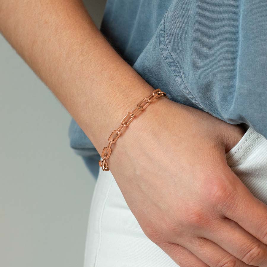 Woman with hand in pocket wearing rose gold paperclip chain medical ID bracelet