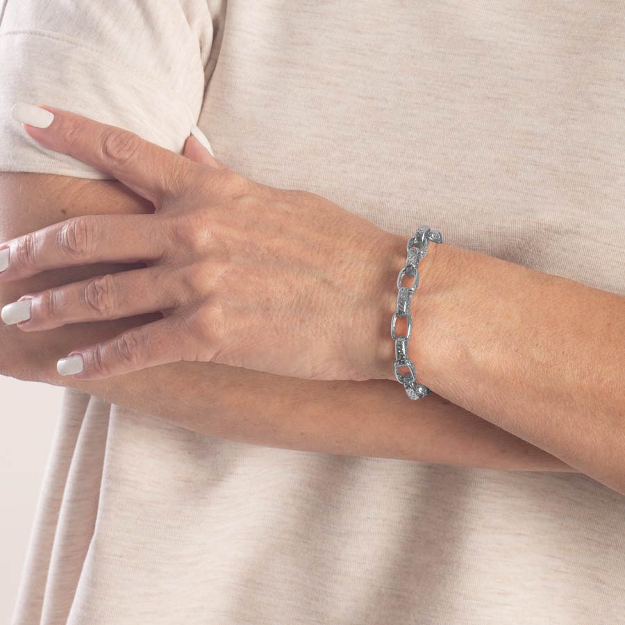 Woman wearing silver tone cutout detailed oval link medical ID chain bracelet.