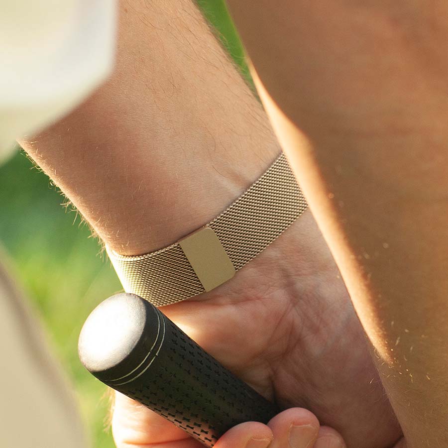 Man holding a golf club wearing sandstone stainless steel medical ID bracelet with magnetic clasp