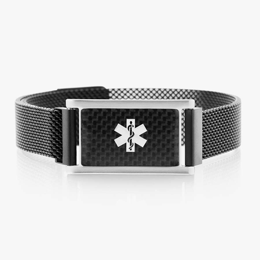 Front of stainless black magnetic bracelet with black mesh chain and affixed medical ID tag with silver caduceus on carbon fiber background