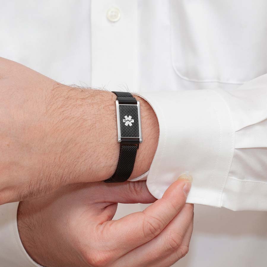 Man in white shirt wearing black stainless steel mesh bracelet with magnetic closure and carbon fiber medical alert tag button his sleeve.