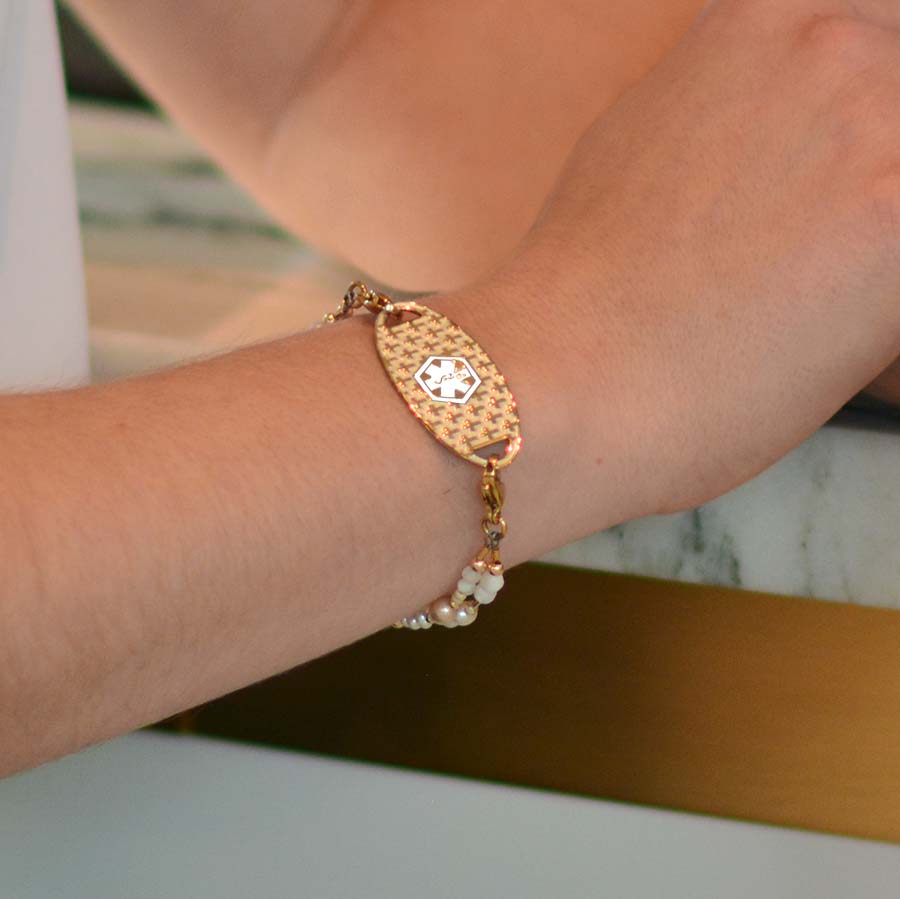 Woman leaning against counter wearing freshwater pearl and gold multistrand beaded bracelet and gold cubic zirconia curb chain bracelet.