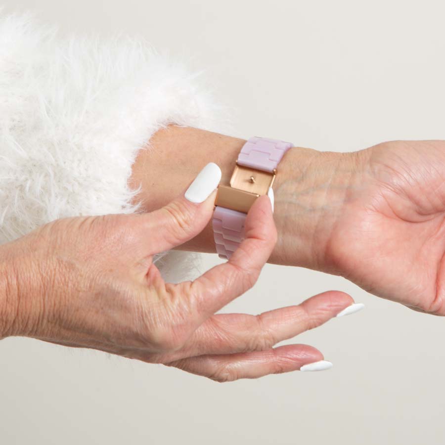 Woman in white sweater wearing lavender resin linked bracelet with rose gold tone stainless steel clasp opening the clasp.