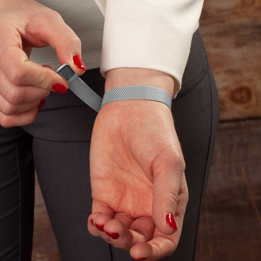 Woman showing magnetic clasp on adjustable stainless steel mesh band bracelet.