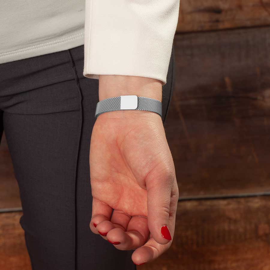 Woman showing magnetic clasp on adjustable stainless steel mesh band bracelet.