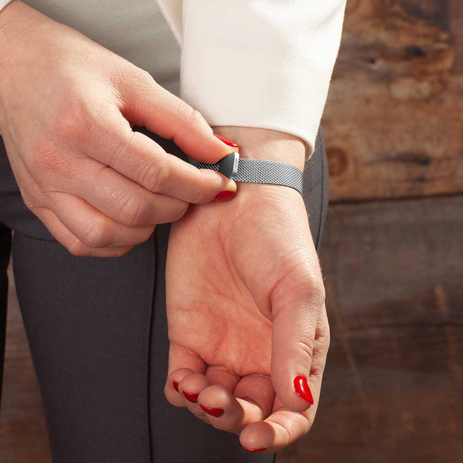 Woman showing magnetic clasp on adjustable stainless steel mesh band bracelet.