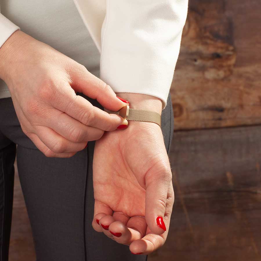 Woman showing adjustable magnetic clasp on stainless steel mesh band bracelet.