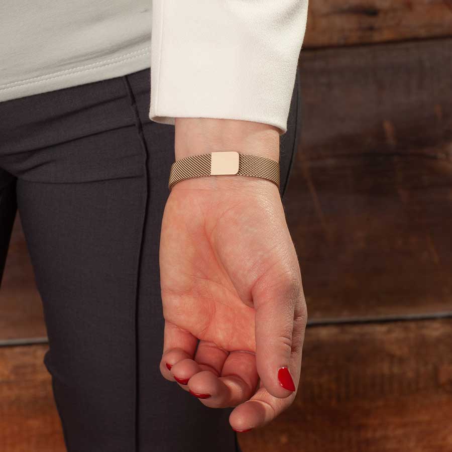 Woman showing adjustable magnetic clasp on stainless steel mesh band bracelet.