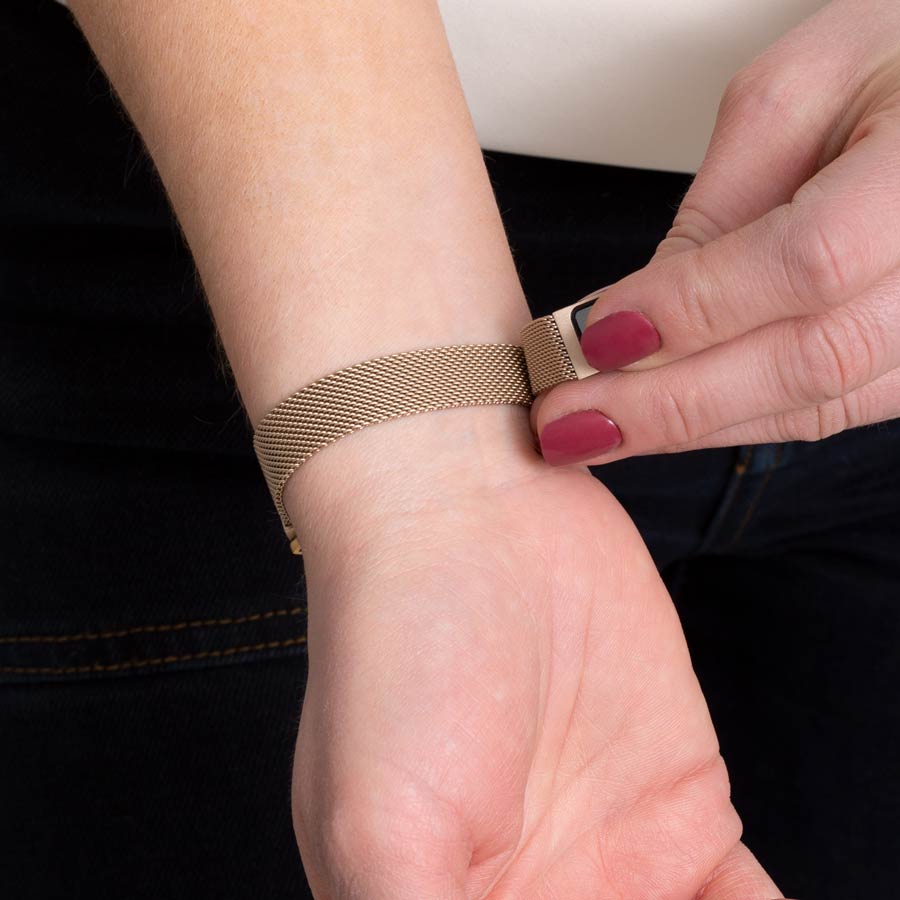 Woman showing how to open magnetic clasp on brushed sandstone magnetic mesh band.