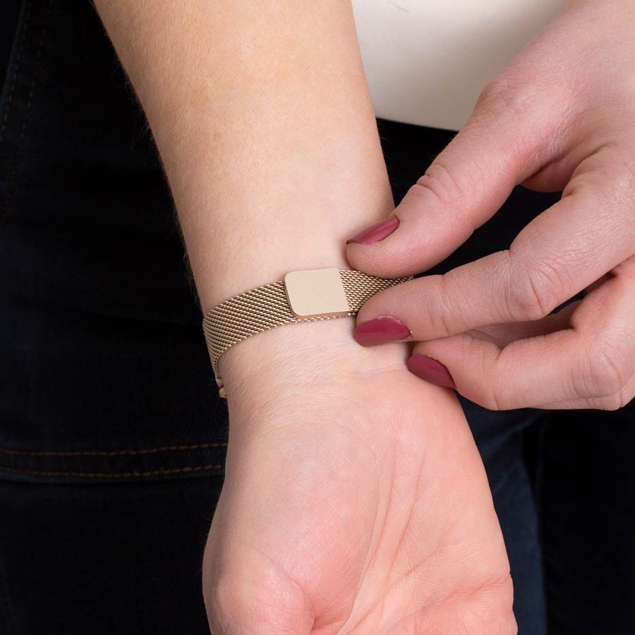 Woman showing how to open magnetic clasp on brushed sandstone magnetic mesh band.